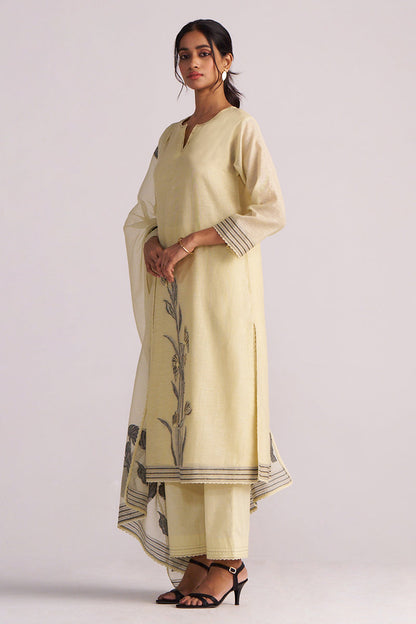 Woman wearing a Butter Yellow Chanderi Woven Kurta Set with black floral patterns on a white background