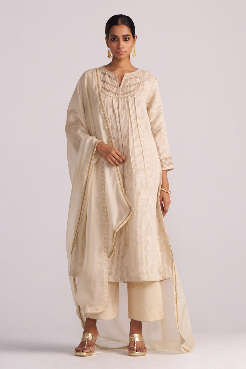 Woman wearing a Beige Woven Kurta Set outfit with a plain background