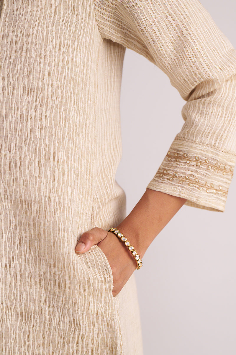 Close-up of a person wearing a Beige Woven Kurta Set with a plain background