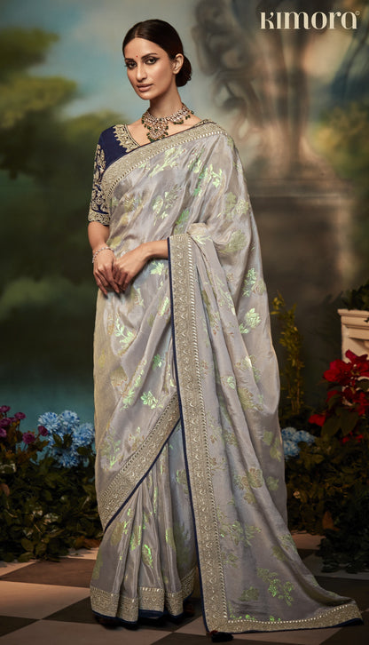 Dhiyona KM Women Pastel Grey Silk Saree With Floral Zari Work And Royal Blue Embroidered Blouse “ Kimora
