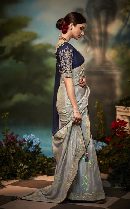 Dhiyona KM Women Pastel Grey Silk Saree With Floral Zari Work And Royal Blue Embroidered Blouse “ Kimora